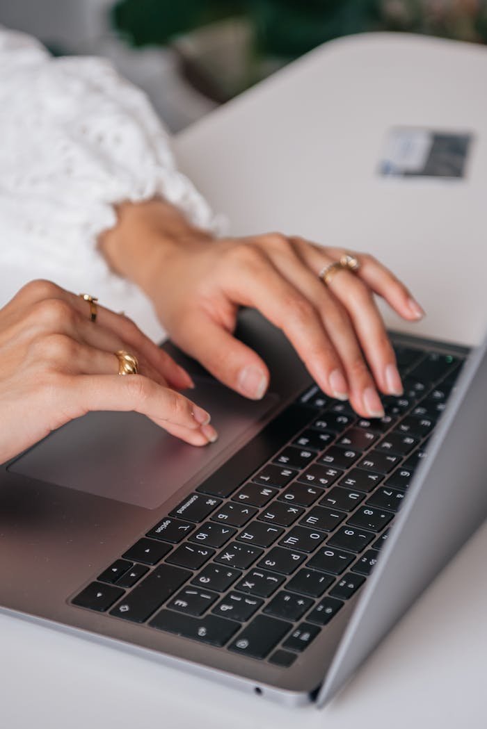Mastering the First Impression: Your intriguing post title goes here Hands of a woman typing on a laptop keyboard indoors, showcasing rings and fashion.